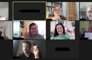 8 people holding a pen in the air as if they are writing