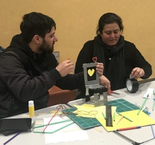 Members talk while making a chair out of card.