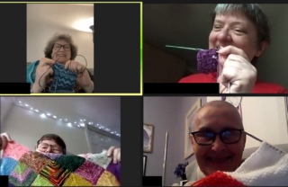 Four people on Zoom share their knitting and blanket making by holding their work up to their faces and smiling.
