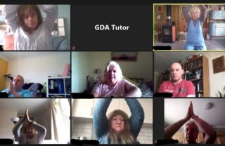 GDA members are on Zoom each raising their hands to touch above their head in a meditative pose.