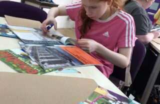 Image of young GDA member doing a craft workshop, she is wearing a pink top and has tied up red hair.