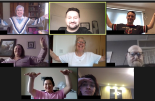 7 GDA members and the tutor are on a Zoom video call. Everyone is smiling at the camera and holding a Tai Chi pose with arms raised and hands out at right angles to the body.