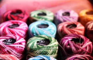 close up image on rows of brightly coloured wool and thread.